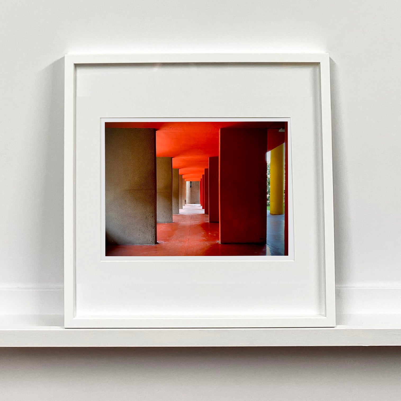 Red and yellow brutalist concrete architecture photograph by Richard Heeps framed in white.