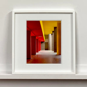 Monte Amiata housing, Gallaratese Quarter, Milan. Red and yellow brutalist architecture photograph by Richard Heeps framed in white.