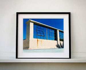 Window of the World, Zzyzx Resort Pool, photographed in Soda Dry Lake, California shows window pains and a distressed wall, against a bright blue background of sky. This artwork is part of Richard's 'Dream in Colour' series. 