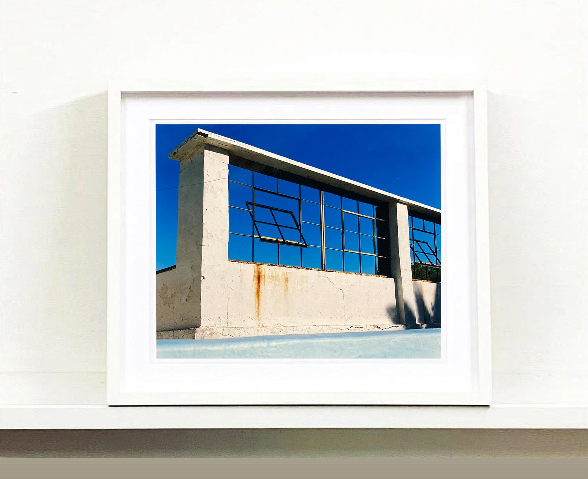 Window of the World, Zzyzx Resort Pool, photographed in Soda Dry Lake, California shows window pains and a distressed wall, against a bright blue background of sky. This artwork is part of Richard's 'Dream in Colour' series. 