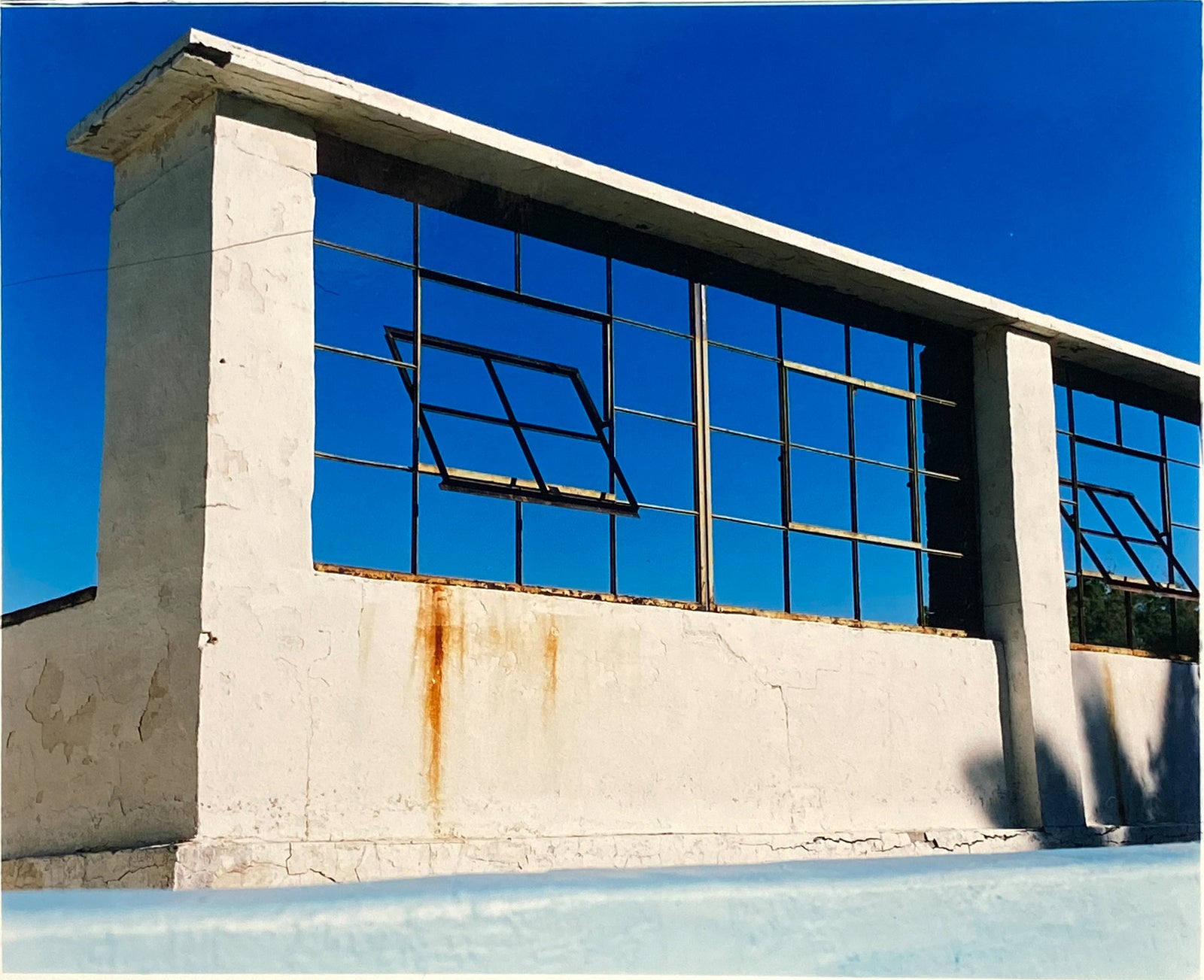 Window of the World, Zzyzx Resort Pool, photographed in Soda Dry Lake, California shows window pains and a distressed wall, against a bright blue background of sky. This artwork is part of Richard's 'Dream in Colour' series. 