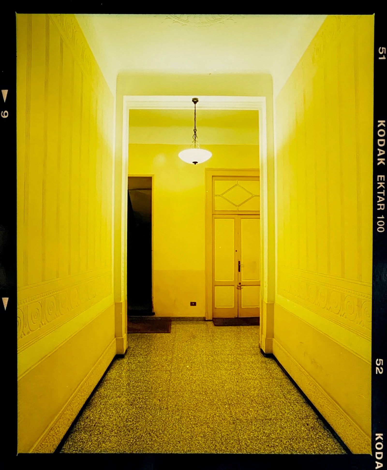 A yellow glow fills the corridor of an apartment foyer in Milan. 