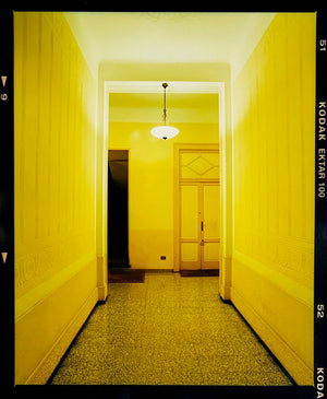 A yellow glow fills the corridor of an apartment foyer in Milan. 